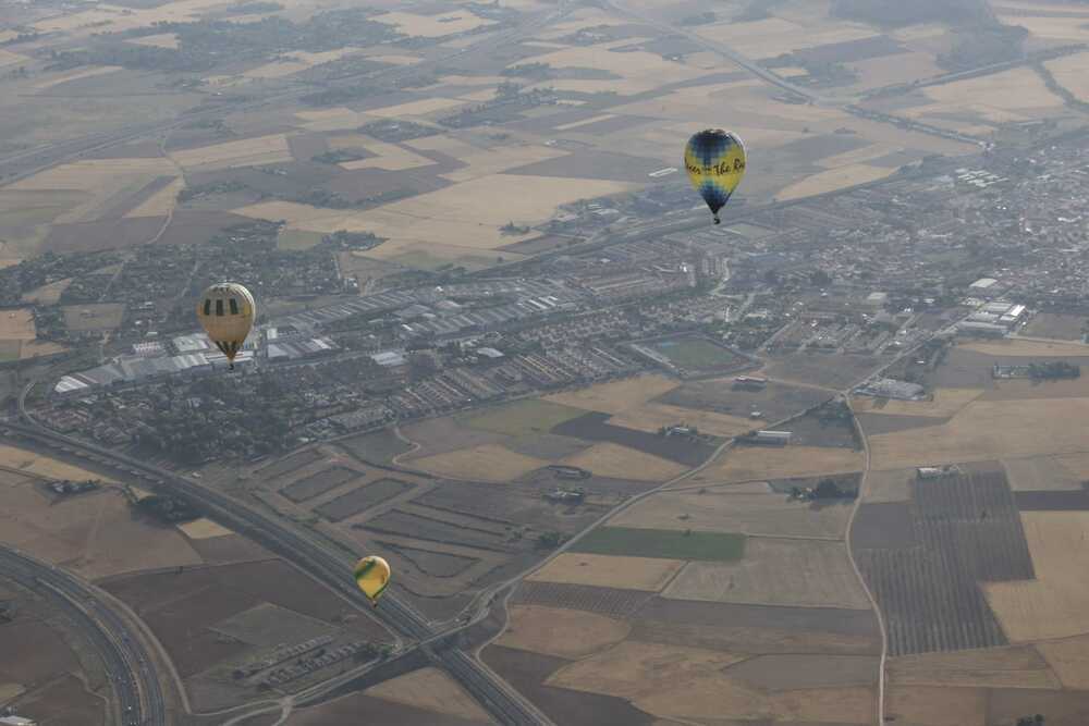 Tres globos en plena competición, con Miguelturra al fondo.