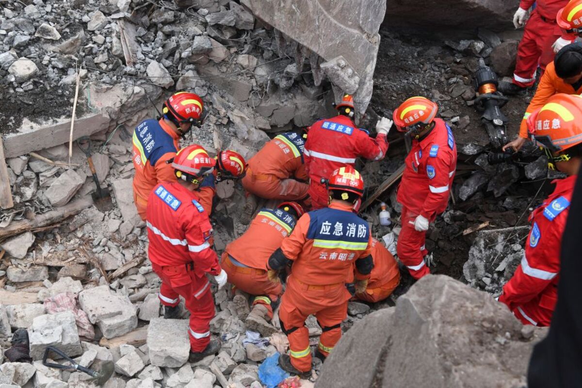 Rescue workers search for survivors in the debris after a landslide hit Zhenxiong County, in Zhaotong  / CHINA DAILY