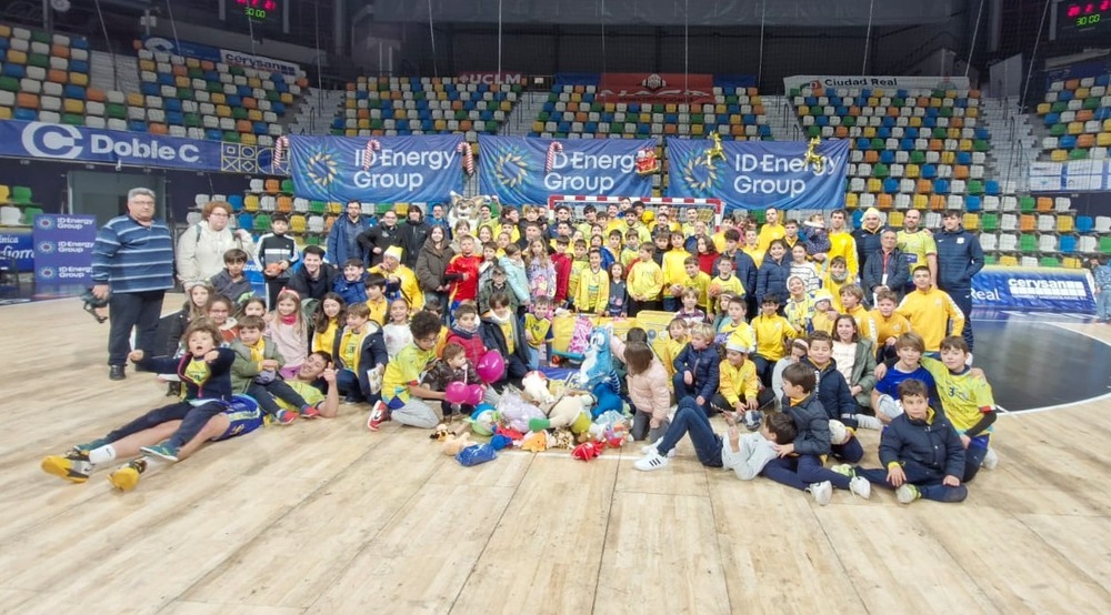 El equipo posa con un grupo de niños delante de los juguetes recogidos.